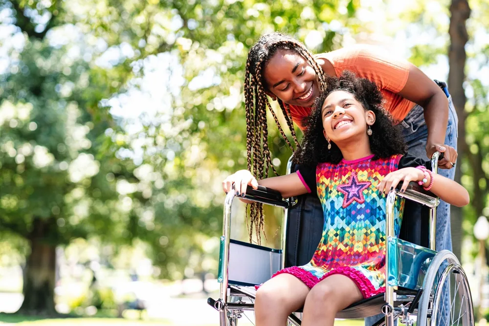 Little girl in a wheelchair at the park with her mother