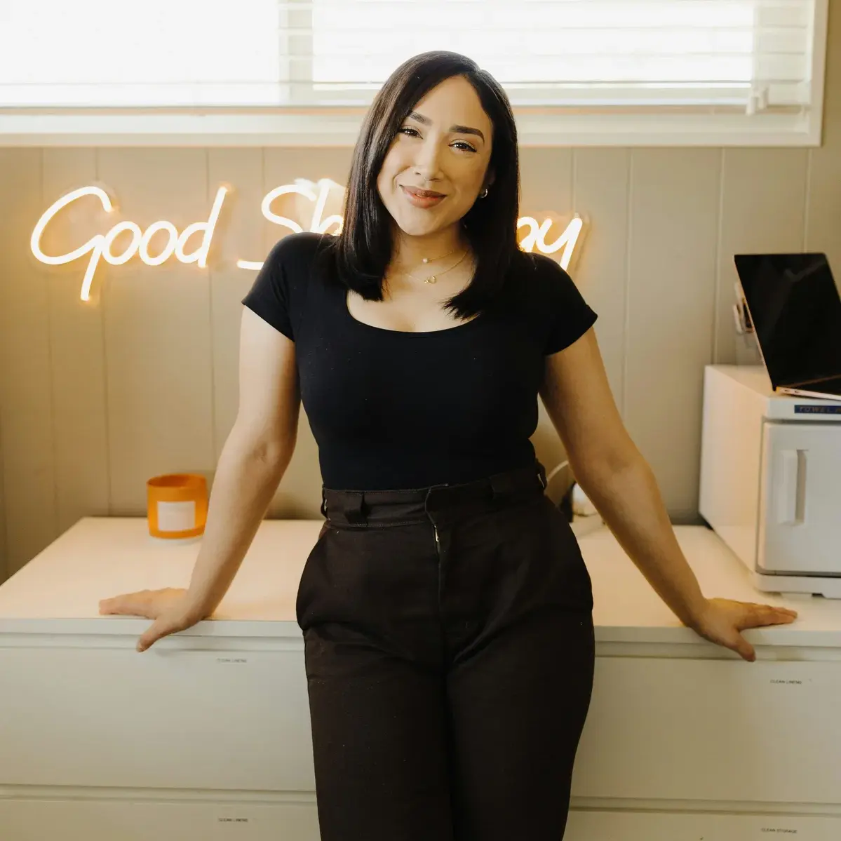 latina woman small business owner standing in front of desk, smiling