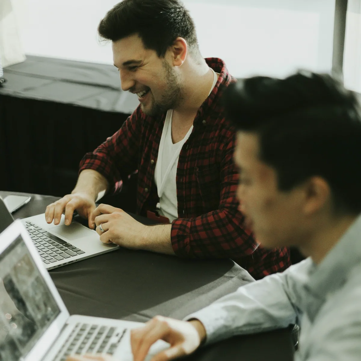 Two men working on laptops together at a table office